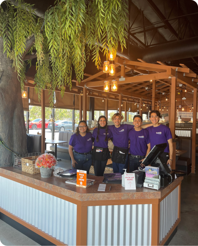 A group of people standing at a cash register.